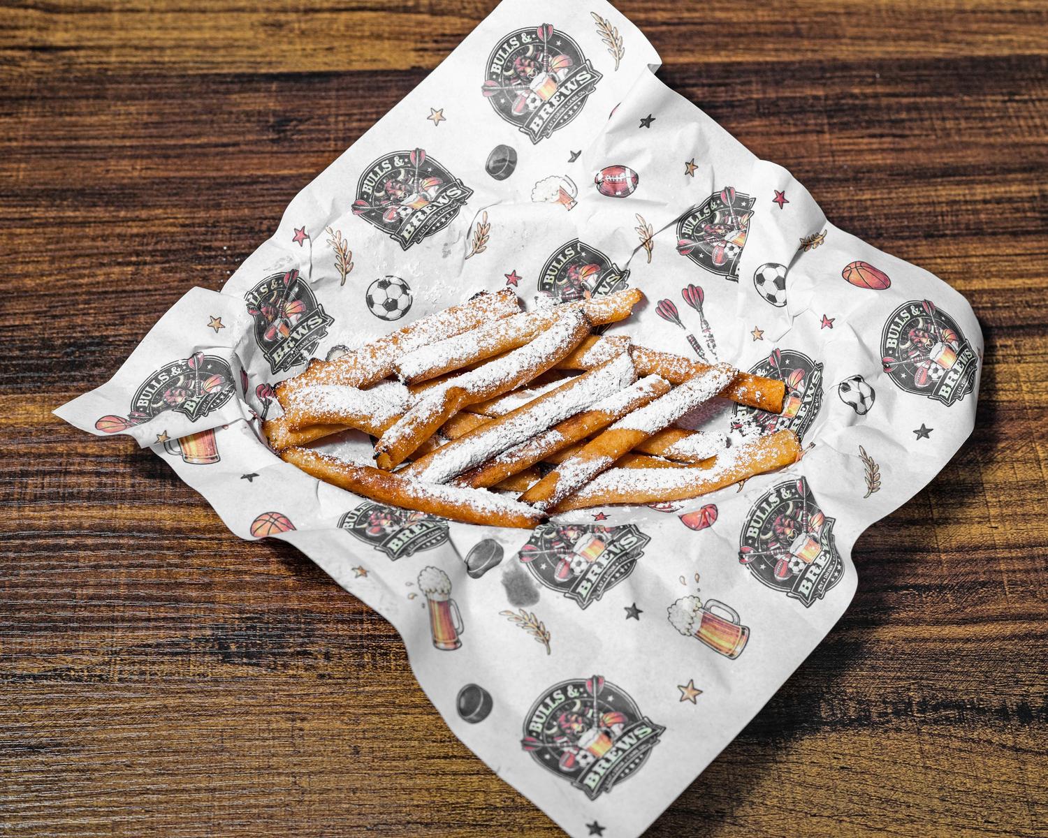 Funnel fries dusted with powdered sugar in a Bulls & Brews paper-lined basket