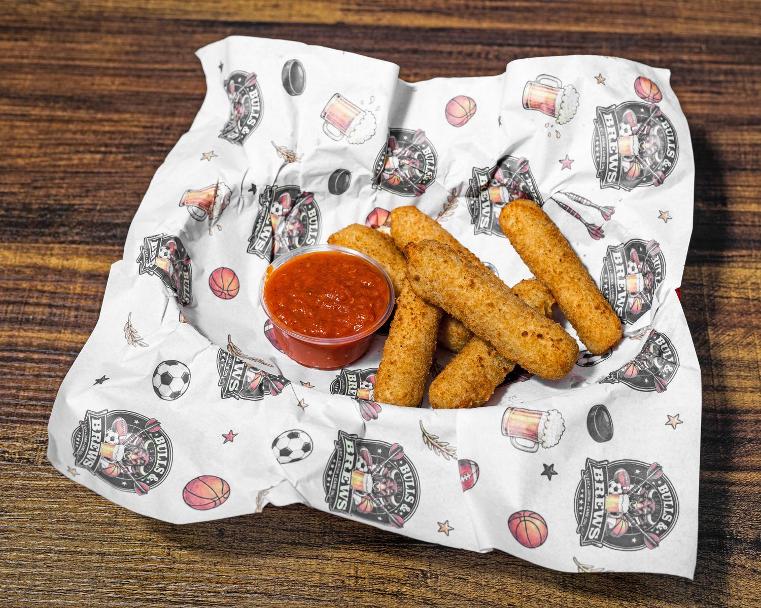 Breaded mozzarella sticks with a cup of marinara sauce