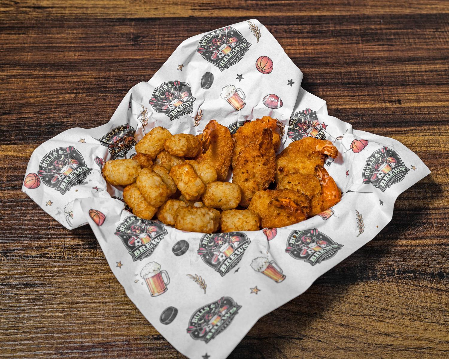 Golden fried shrimp and tater tots in a basket lined with Bulls & Brews paper