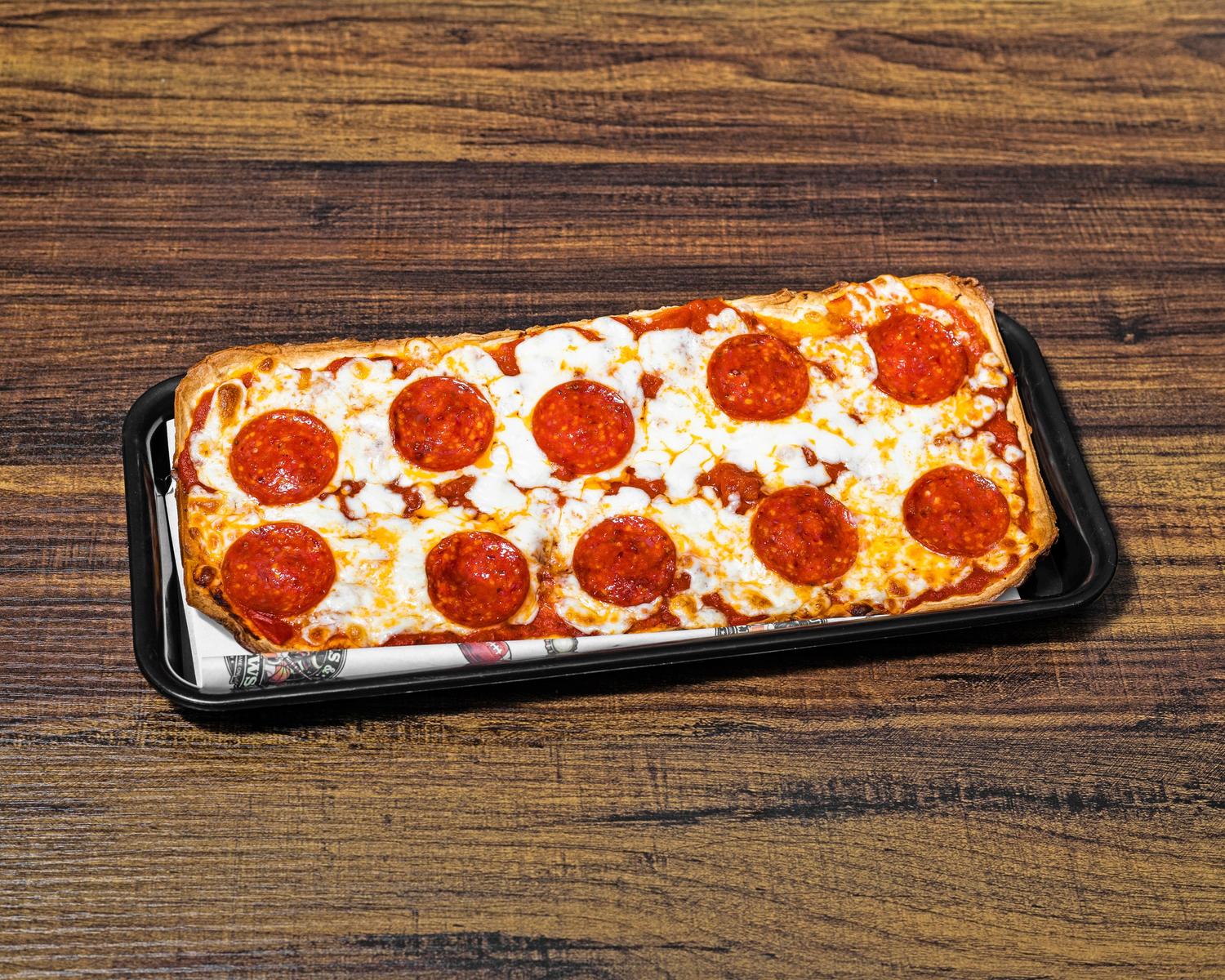 Rectangular pepperoni flatbread pizza on a black serving tray