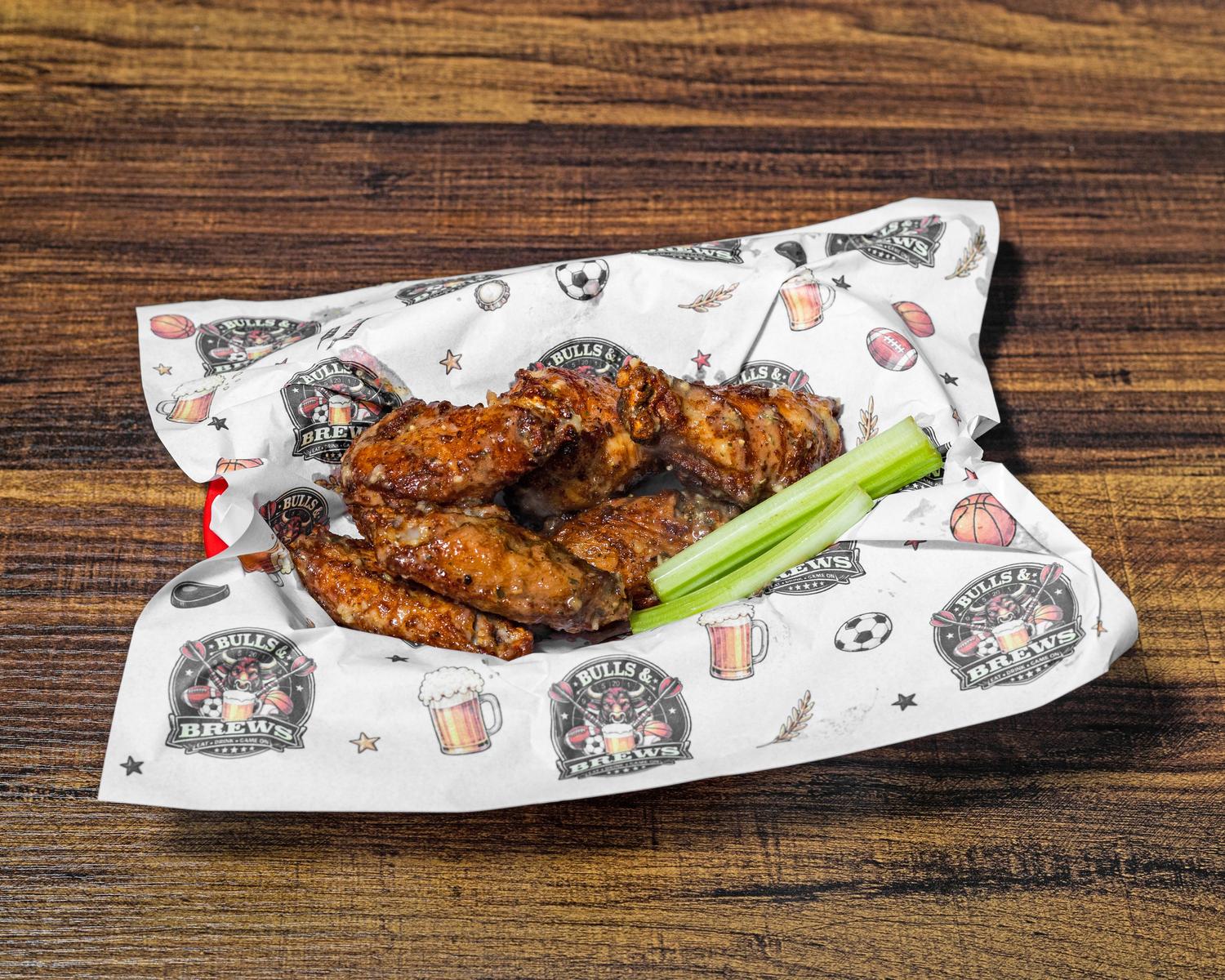 Six jumbo chicken wings with celery sticks in a paper-lined basket